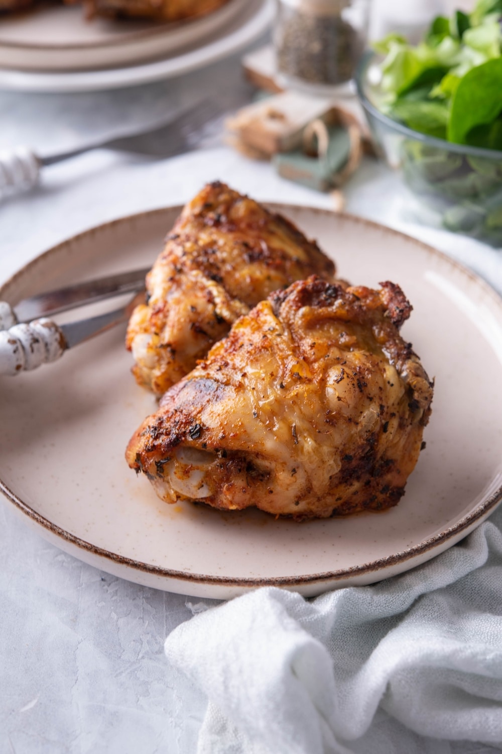 Close up of air fryer chicken thighs on a plate with a knife and fork.