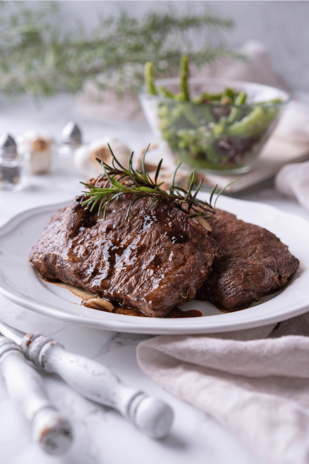 Two cast iron steaks overlapping one another on a white plate.