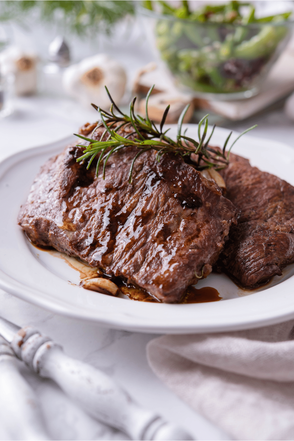 Two juicy cast iron steaks on a white plate.