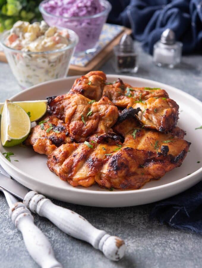 A few gilled chicken thighs that are on a white plate.