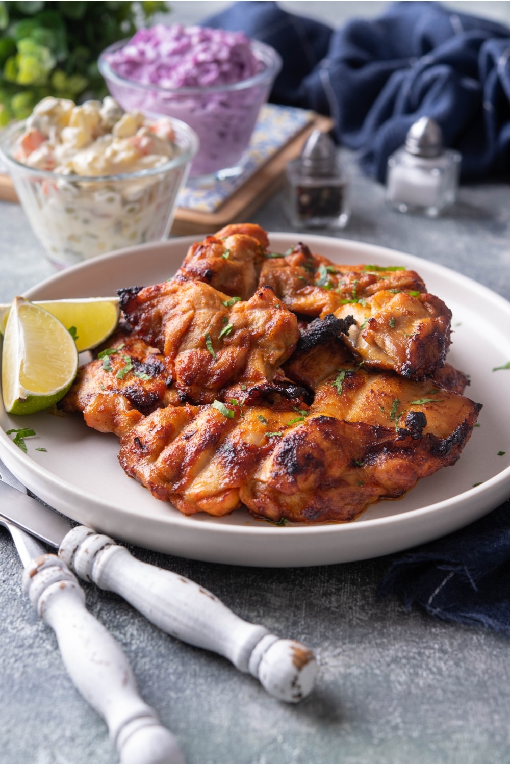 A few gilled chicken thighs that are on a white plate.