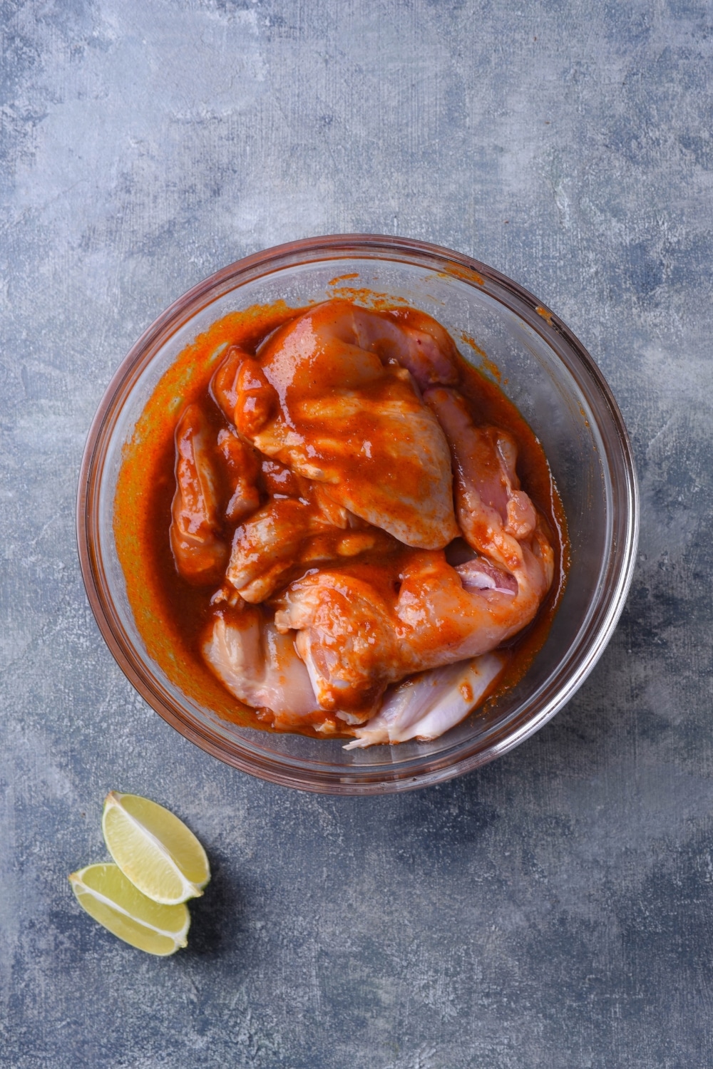 Chicken thighs in a bowl of barbecue sauce.