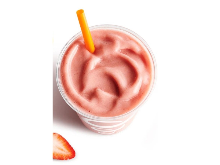 A strawberry smoothie in a cup with a straw.