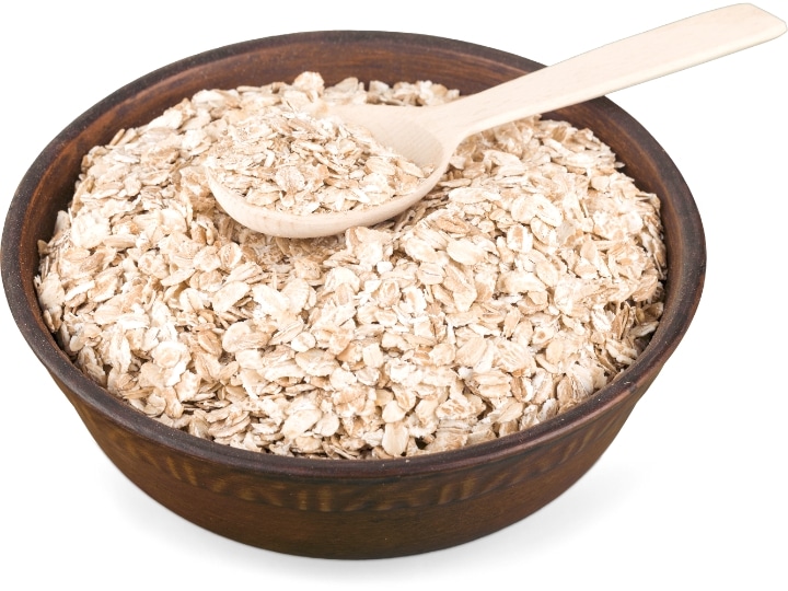 A bowl of uncooked oats with a spoon in it.