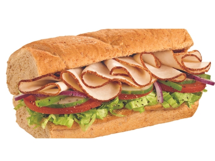 A turkey sub that has tomatoes, lettuce, tomatoes, and onion.