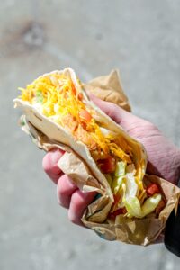 A hand holding a taco bell grilled chicken soft taco supreme.