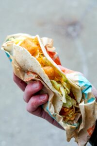 A hand holding a taco bell spicy potato taco.