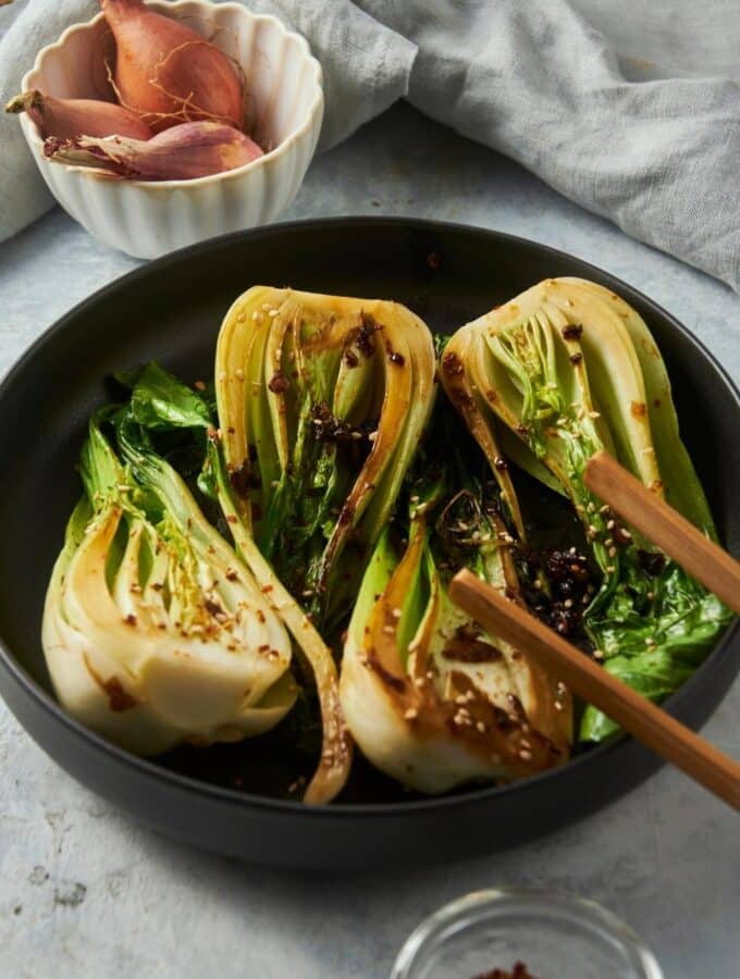 Four pieces of cooked bok choy in a skillet.