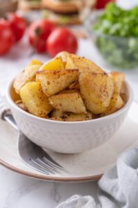 Sauteed chopped potatoes in a white bowl.