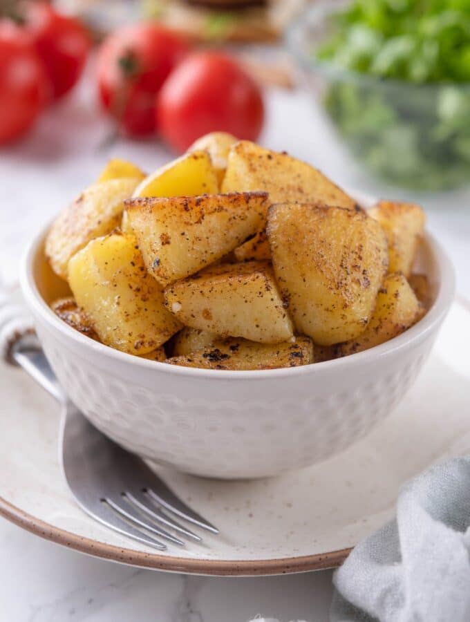 Sauteed chopped potatoes in a white bowl.