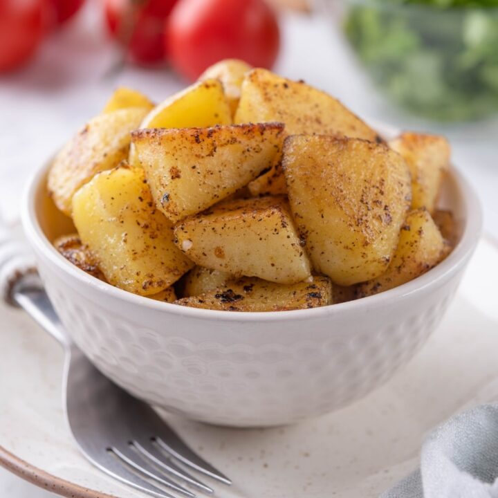 Sauteed chopped potatoes in a white bowl.