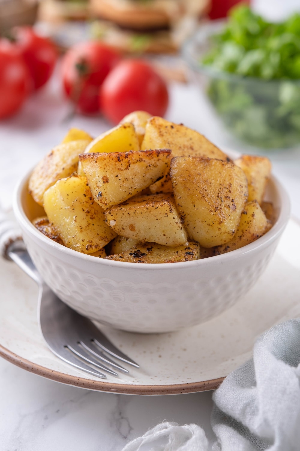 Sauteed chopped potatoes in a white bowl.