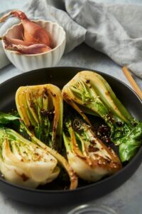 A bunch of cooked bok choy halves in a skillet.