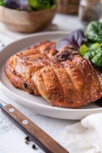 Close up of broiled bone-in pork chops on a plate with a side of salad greens.