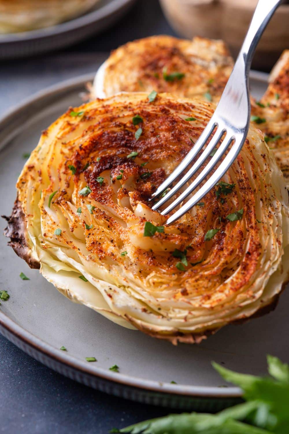 Close up of a fork digging into a tender roasted cabbage steak.