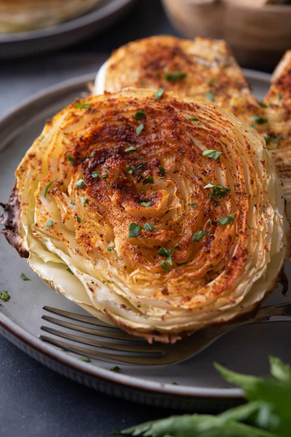 Closer look at a cabbage steak on a plate with a fork.