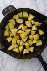 Chopped uncooked potatoes in a cast iron skillet.