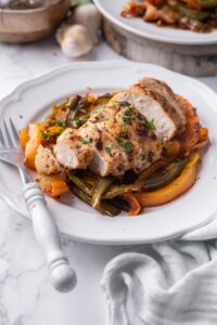 Baked chicken and bell peppers on a white plate with a fork.