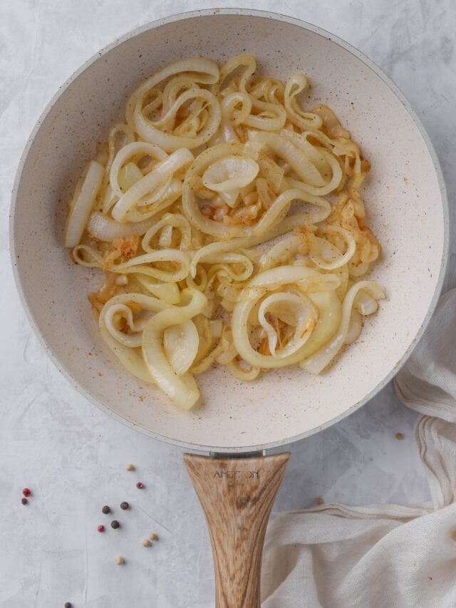 Sauteed onion slices in a white skillet.