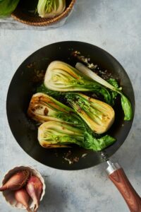 Four bok choy halves cooking in a skillet.