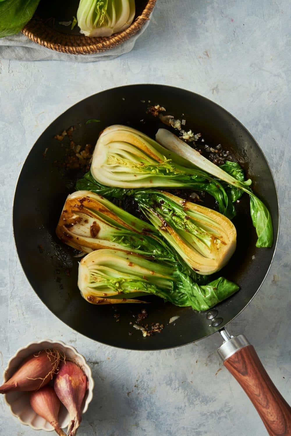 Four bok choy halves cooking in a skillet.