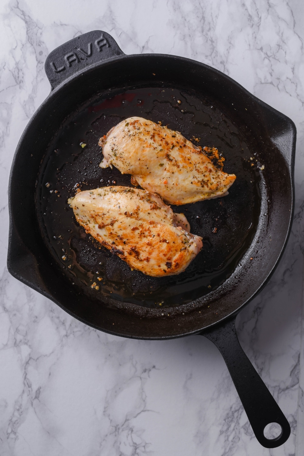 Seared seasoned chicken breasts in a cast iron skillet.