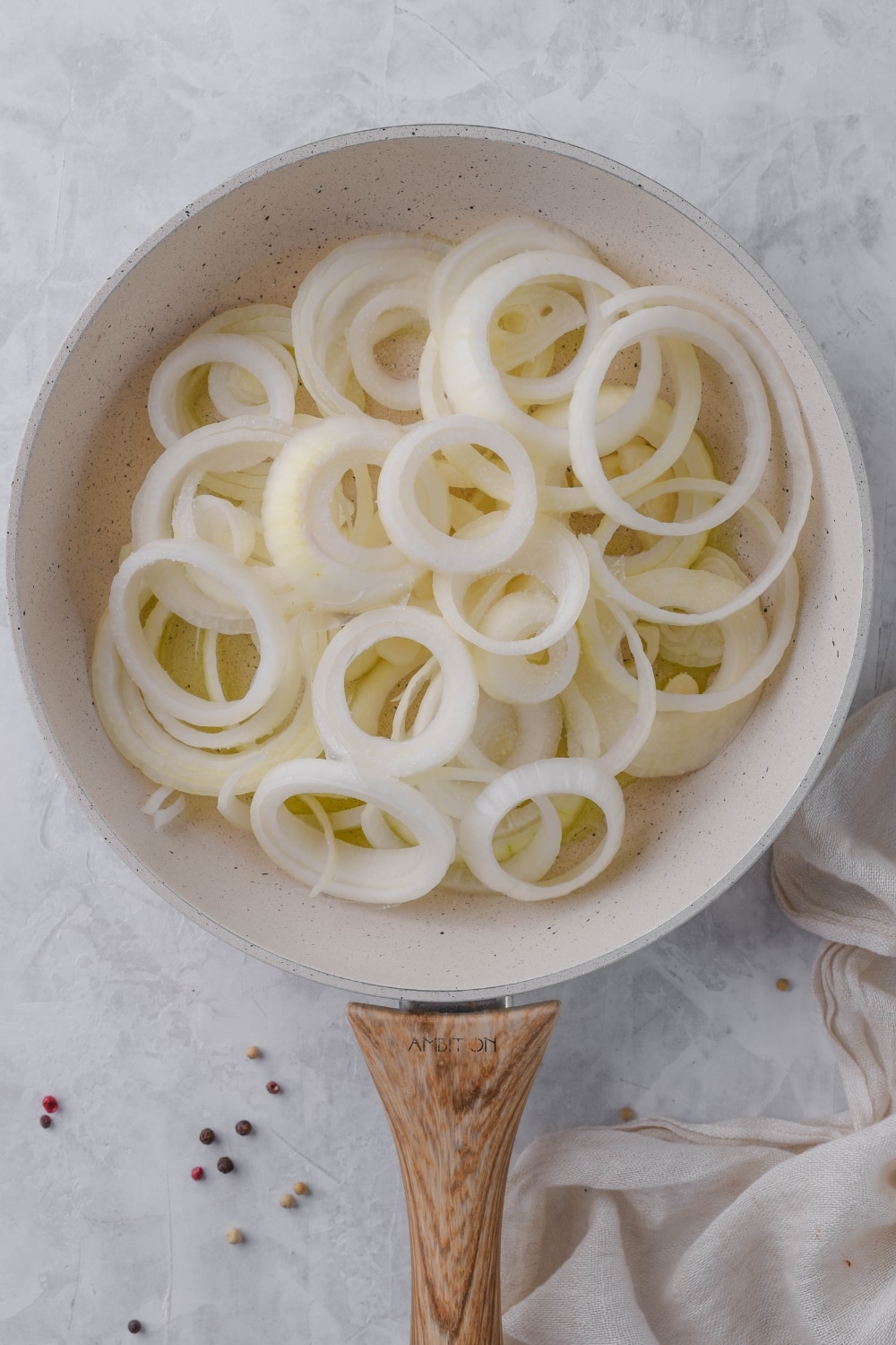 Raw onion slices in a white skillet.