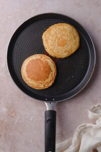 Two oat flour pancakes on a non-stick skillet.