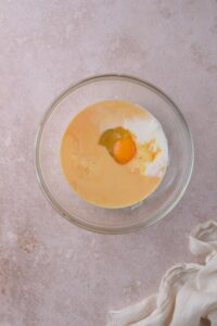 A glass bowl filled with milk, lemon juice, sugar, and raw egg.