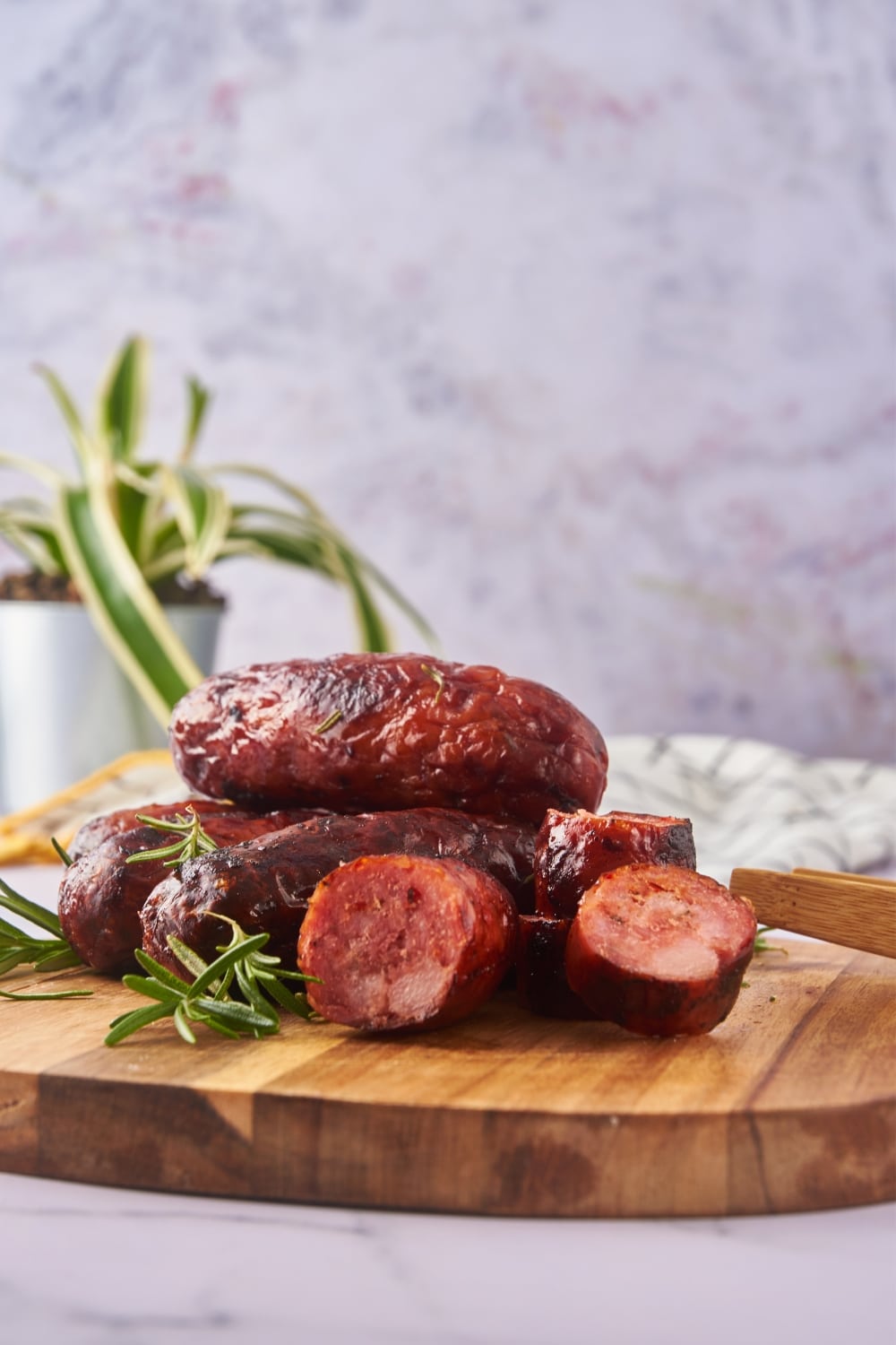 Oven roasted sausages, one sliced into bite-sized pieces, served on a wooden serving board.