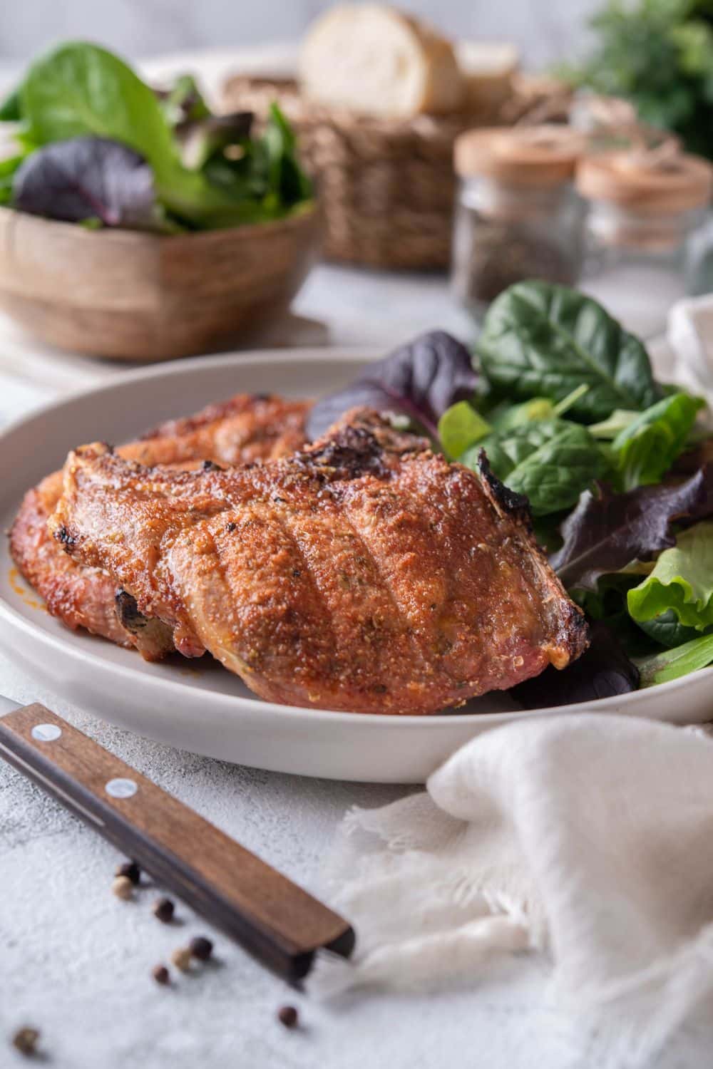 Broiled spice rubbed pork chops with a side of salad greens on a plate.