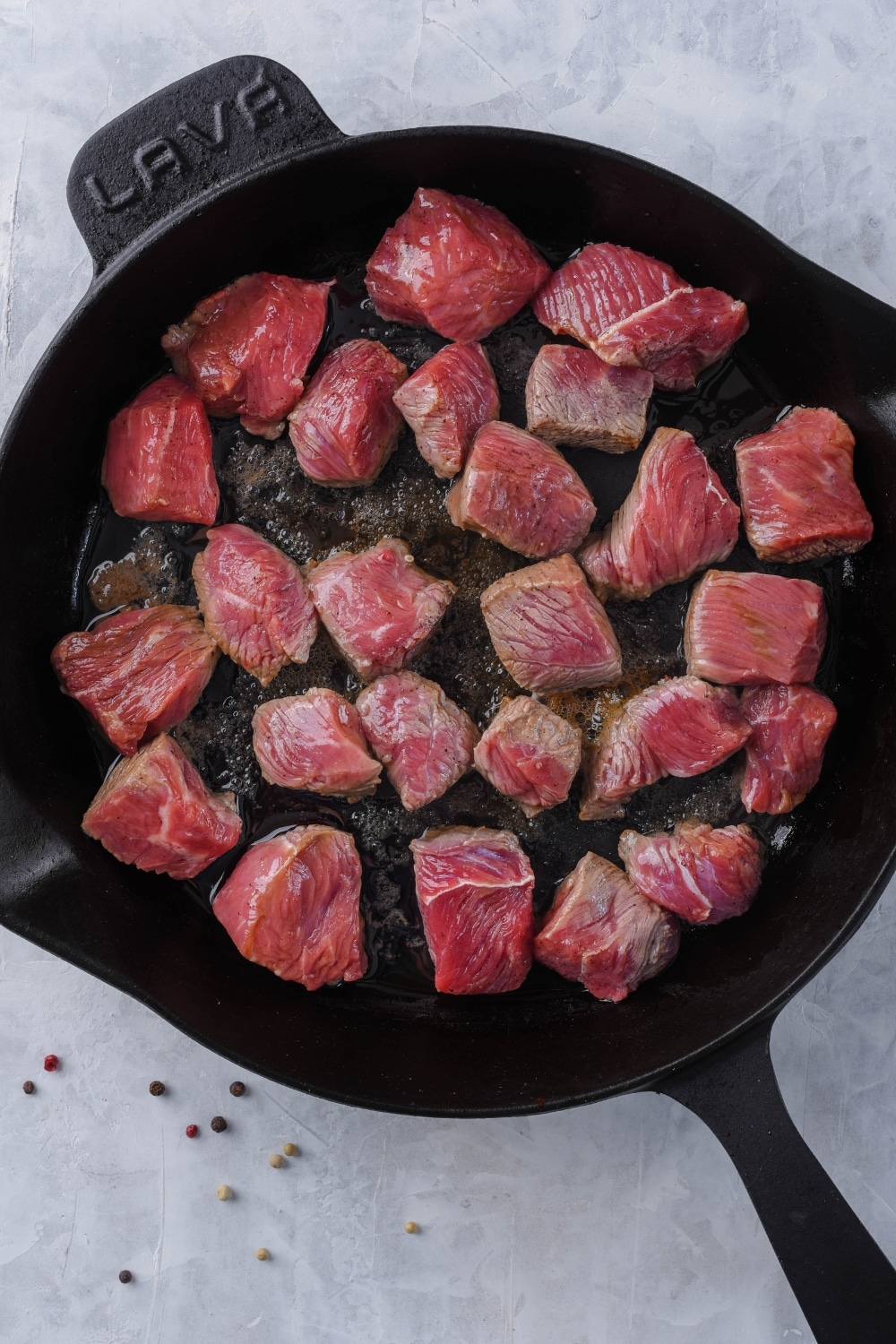 Partially cooked steak tips searing in a cast iron skillet.