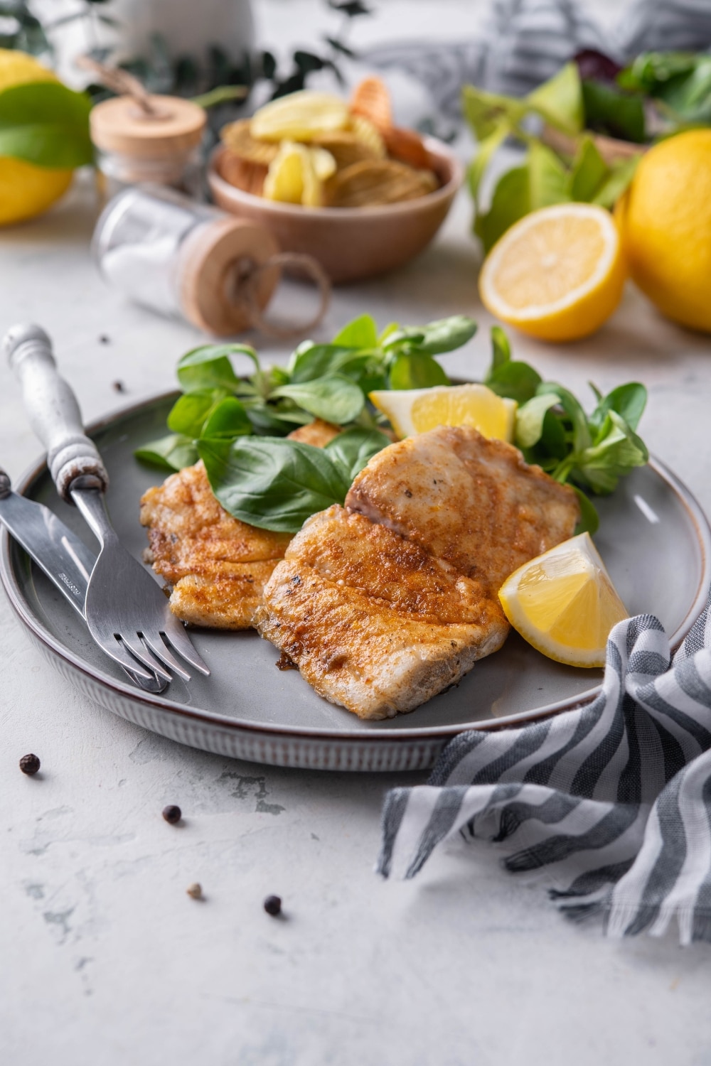 Grilled halibut filets garnished with lemon wedges and served with a side of salad.