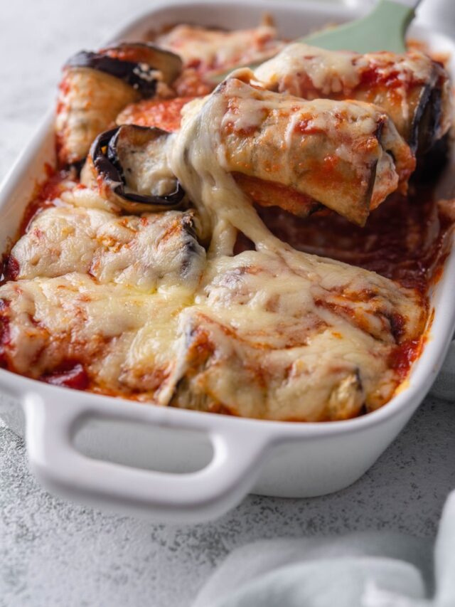 Eggplant rollatini in a casserole dish topped with melty, stretchy cheese.