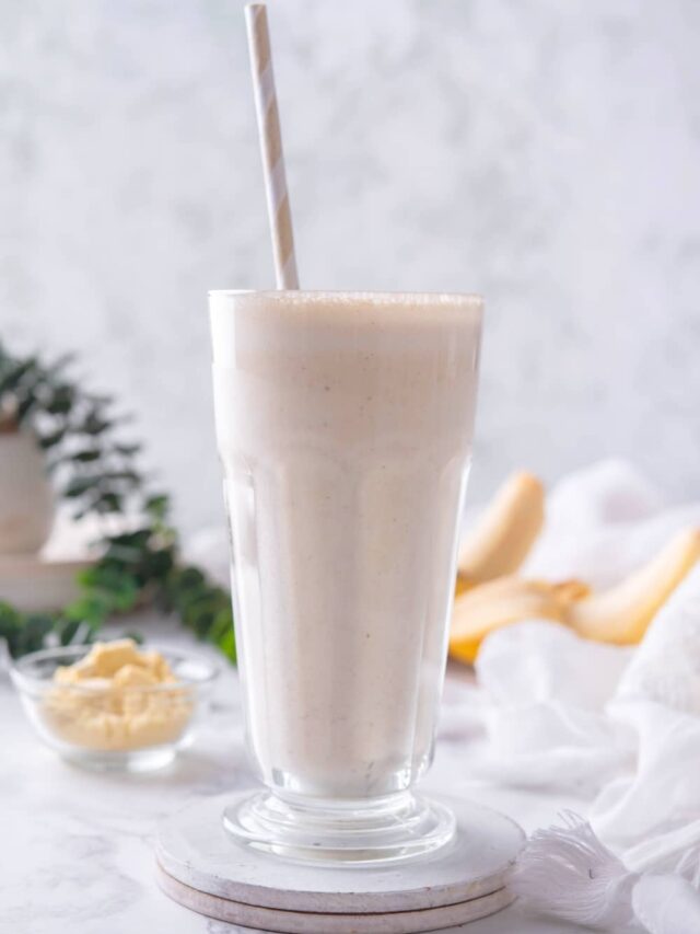 A straw in a glass that has a banana protein shake in it.