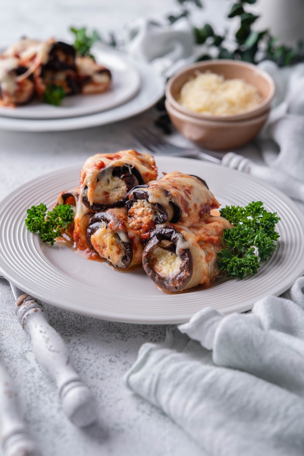 Eggplant rollatini on a white plate garnished with curly parsley.