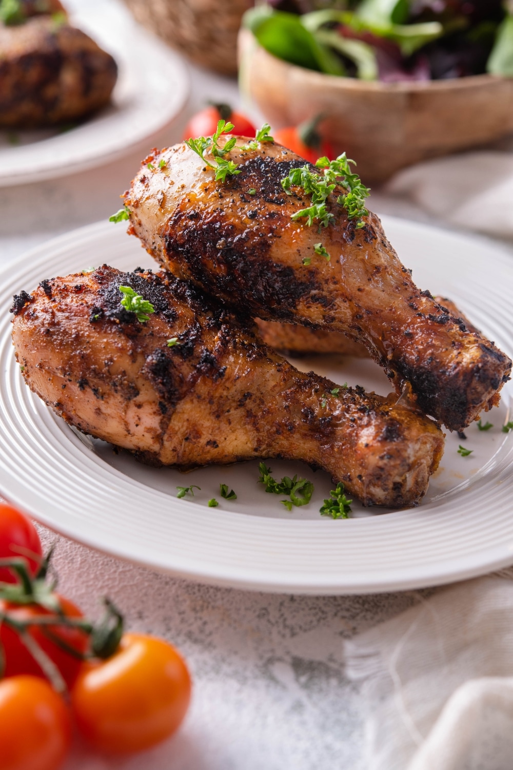 A closer look at grilled chicken drumsticks on a plate with parsley for garnish.