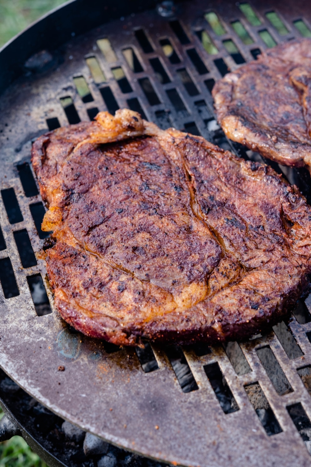 Grilled ribeye steaks on a charcoal grill.