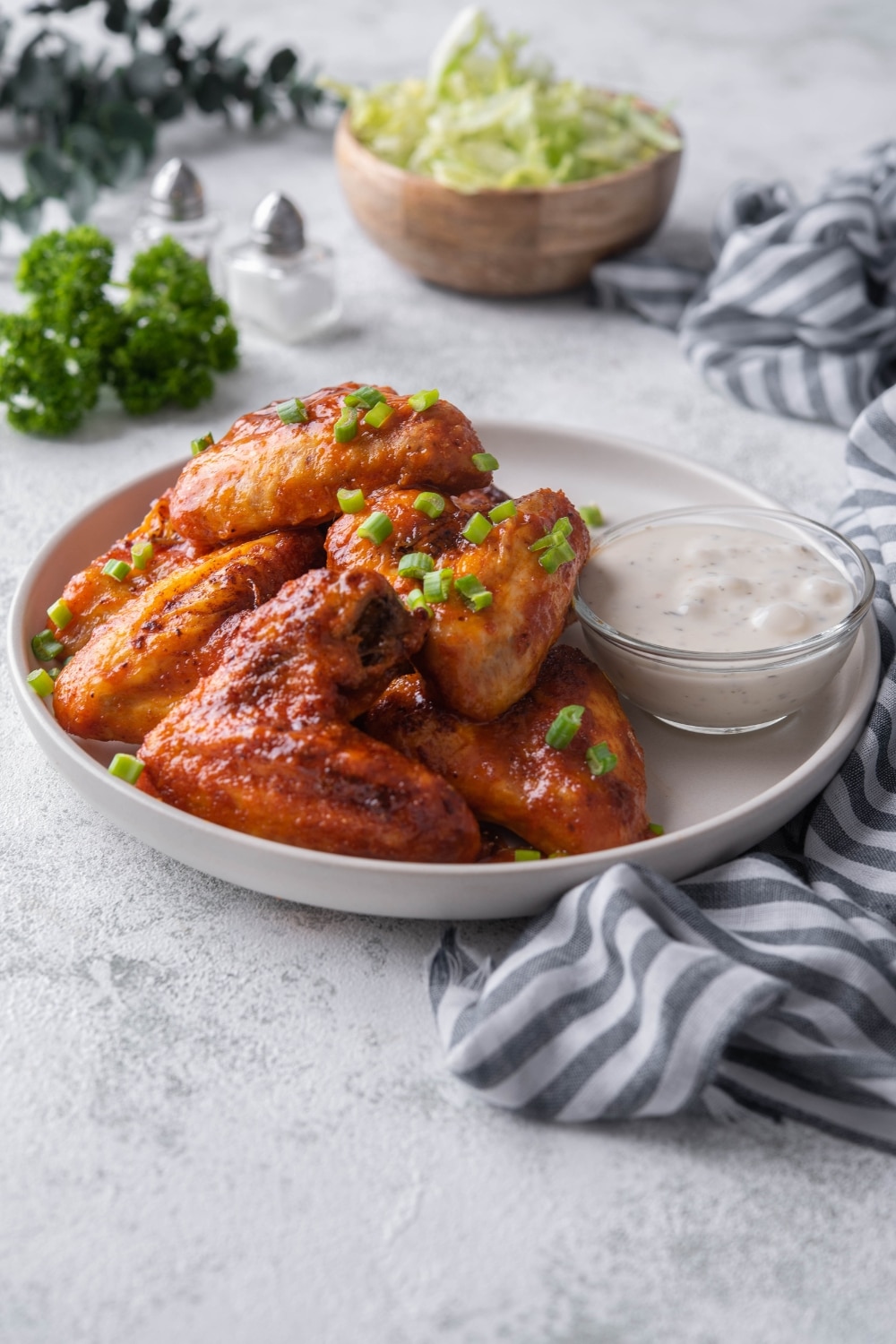 Baked hot wings topped with chopped green onions and served with a small bowl of ranch.