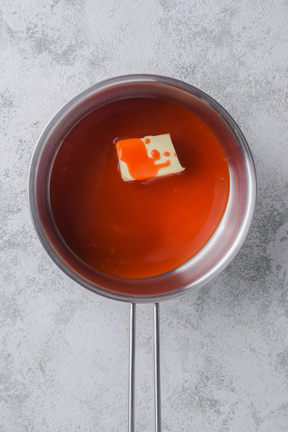 A knob of butter in a saucepan filled with hot sauce.
