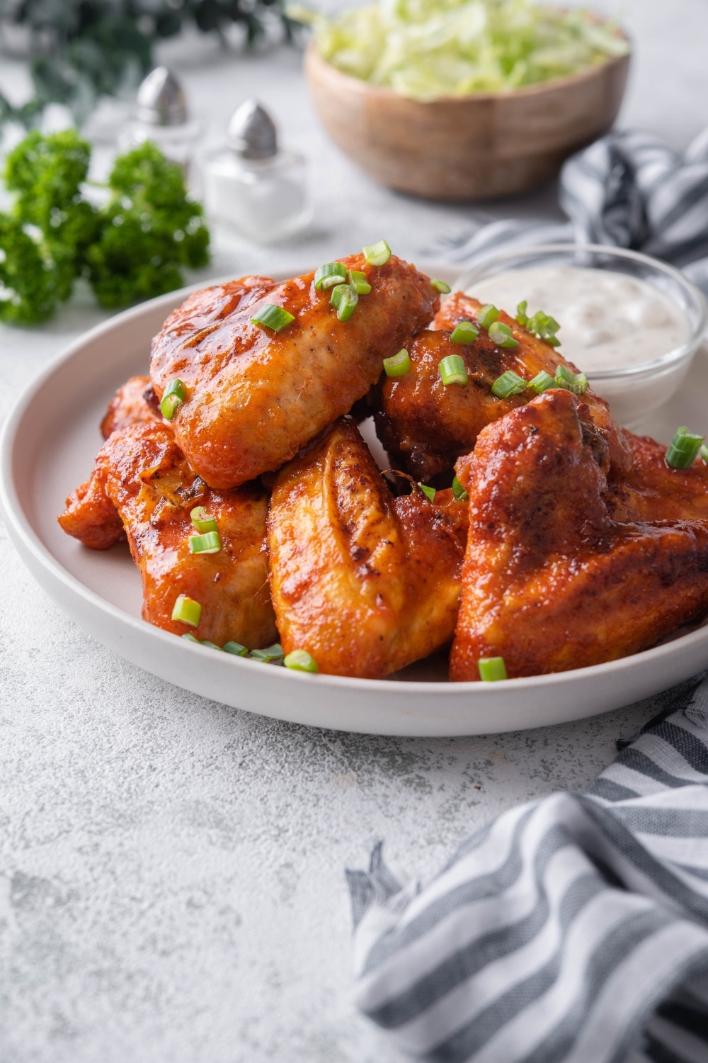 Baked chicken wings garnished with chopped green onions and served with ranch.