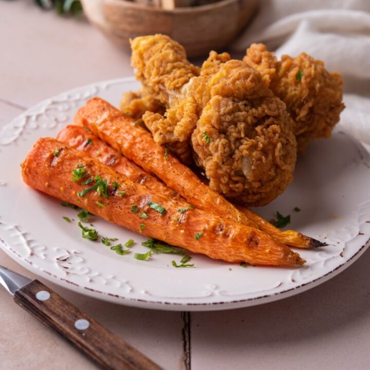 Grilled carrots served with fried chicken and garnished with parsley.