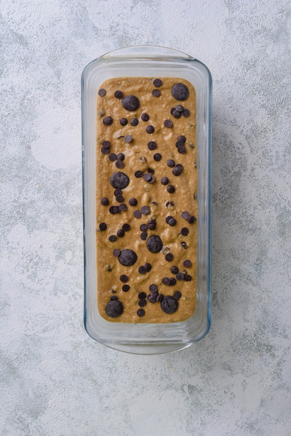 Uncooked banana bread batter topped with chocolate chips in a loaf pan.