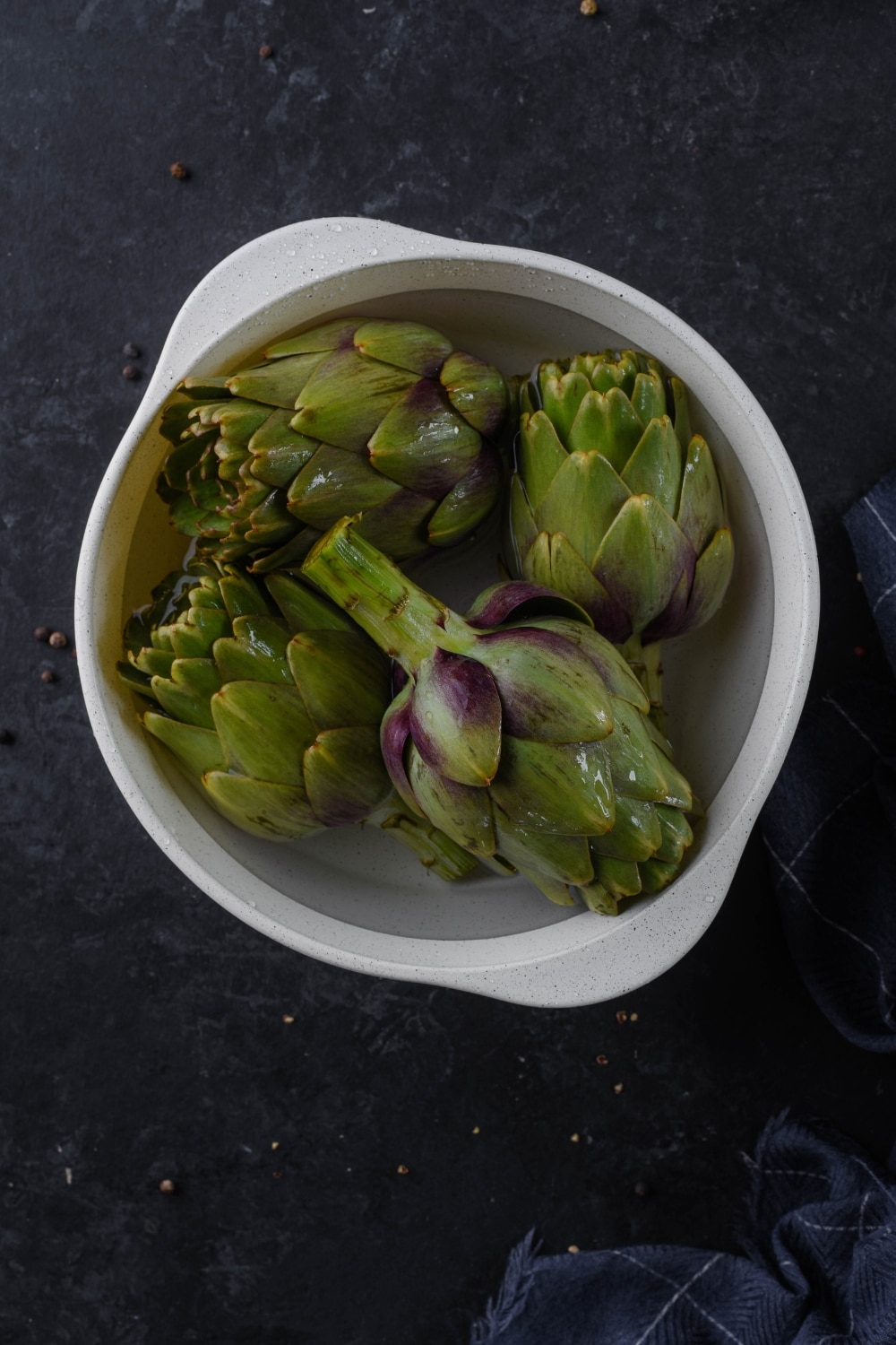 Boiled artichokes in a white pot.