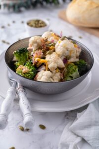 Broccoli and cauliflower salad served in a grey bowl over a white plate.