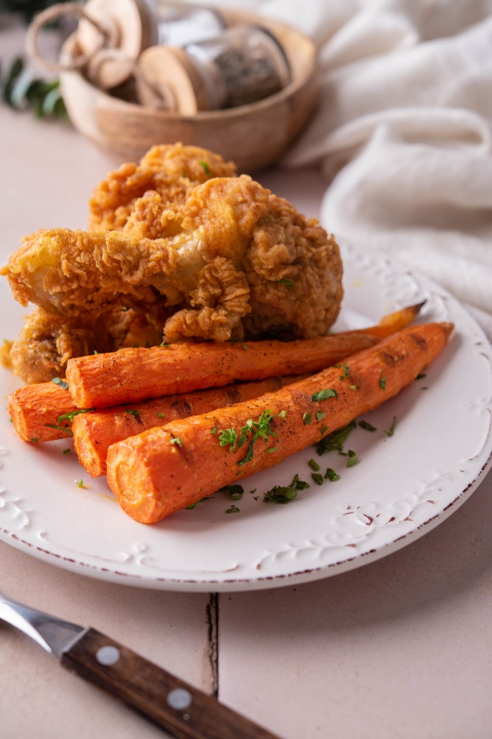 Grilled carrots and fried chicken served on a white plate.