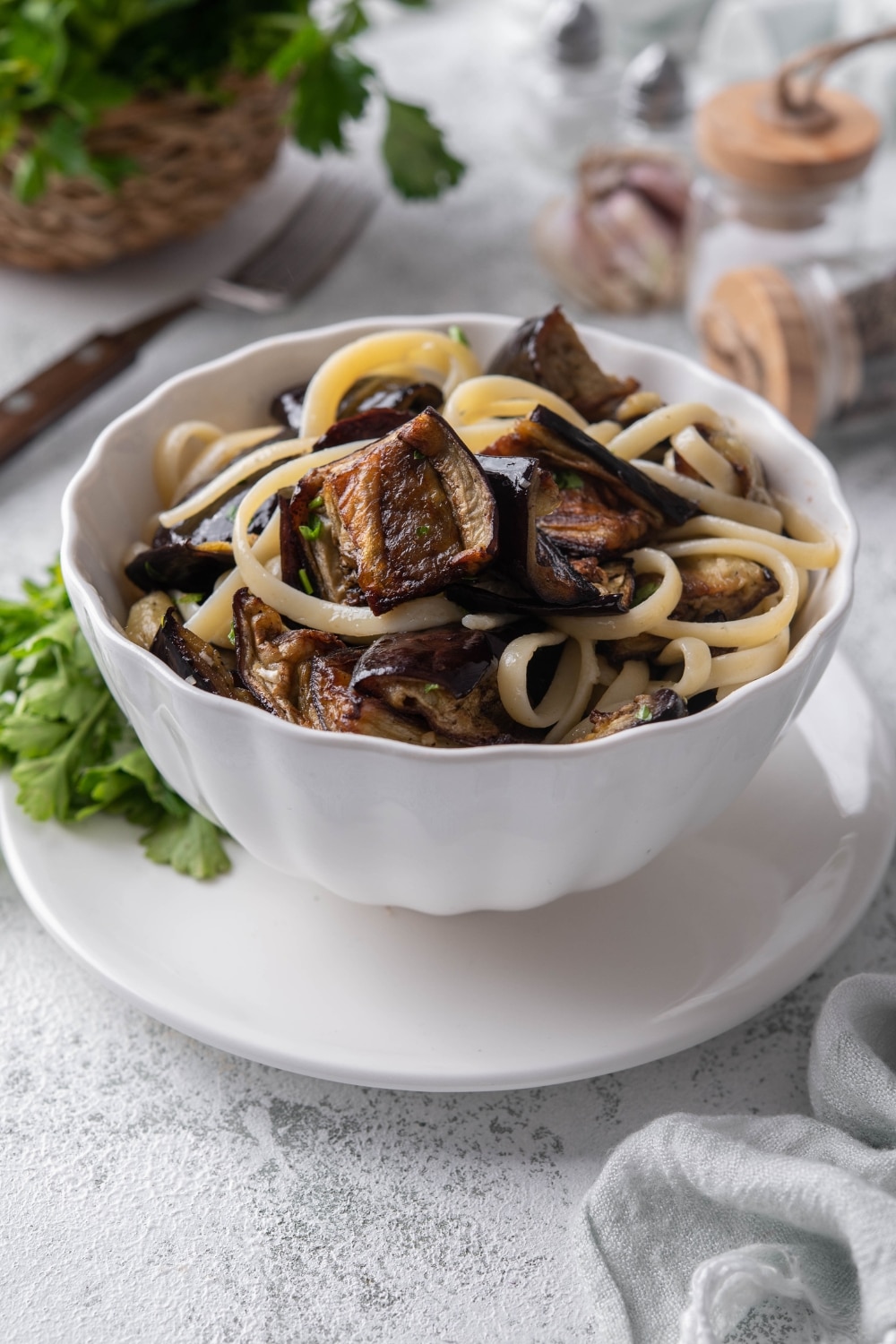 Roasted eggplant pasta in a bowl set over a plate garnished with fresh parsley.