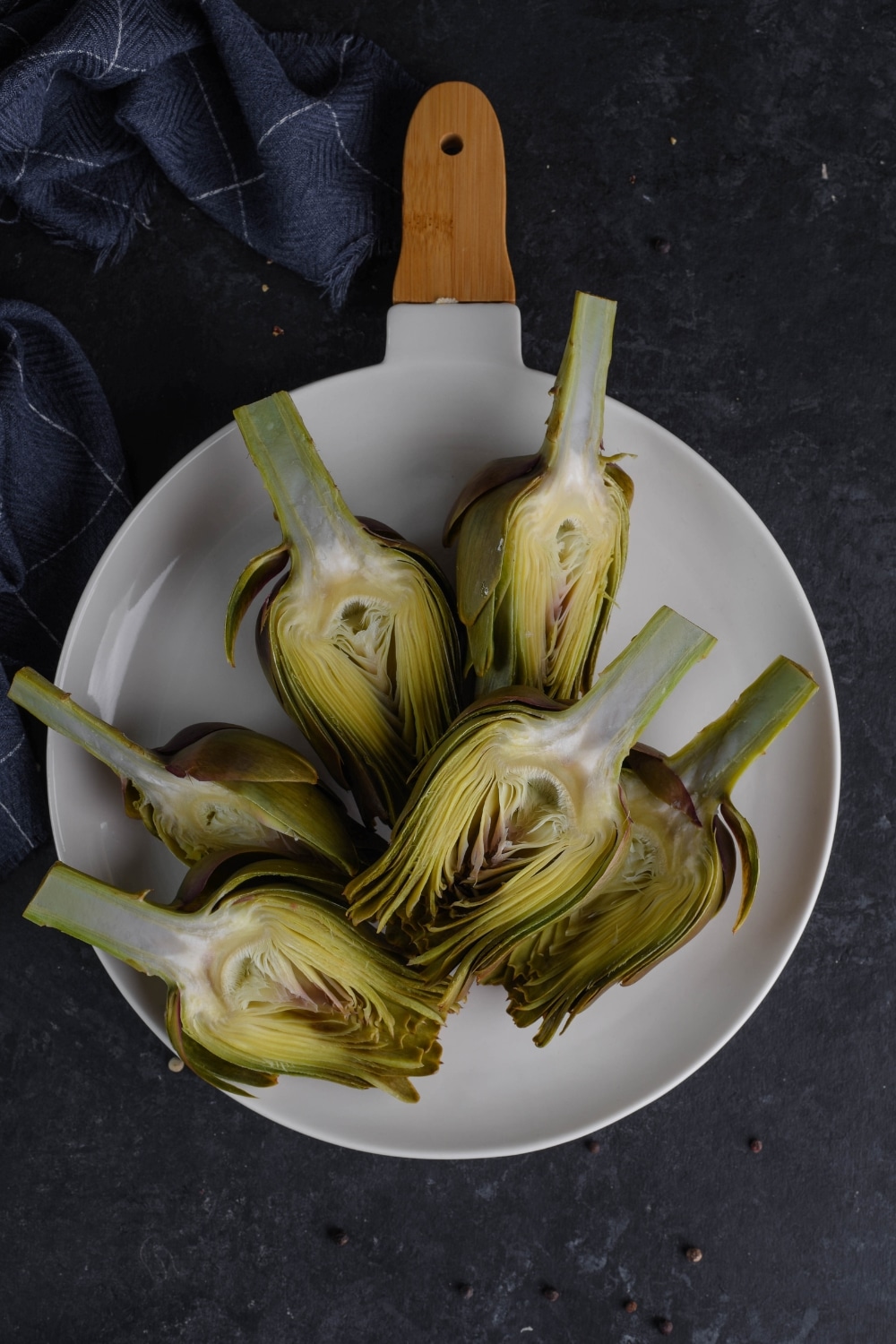 Six artichoke halves in a white pan.