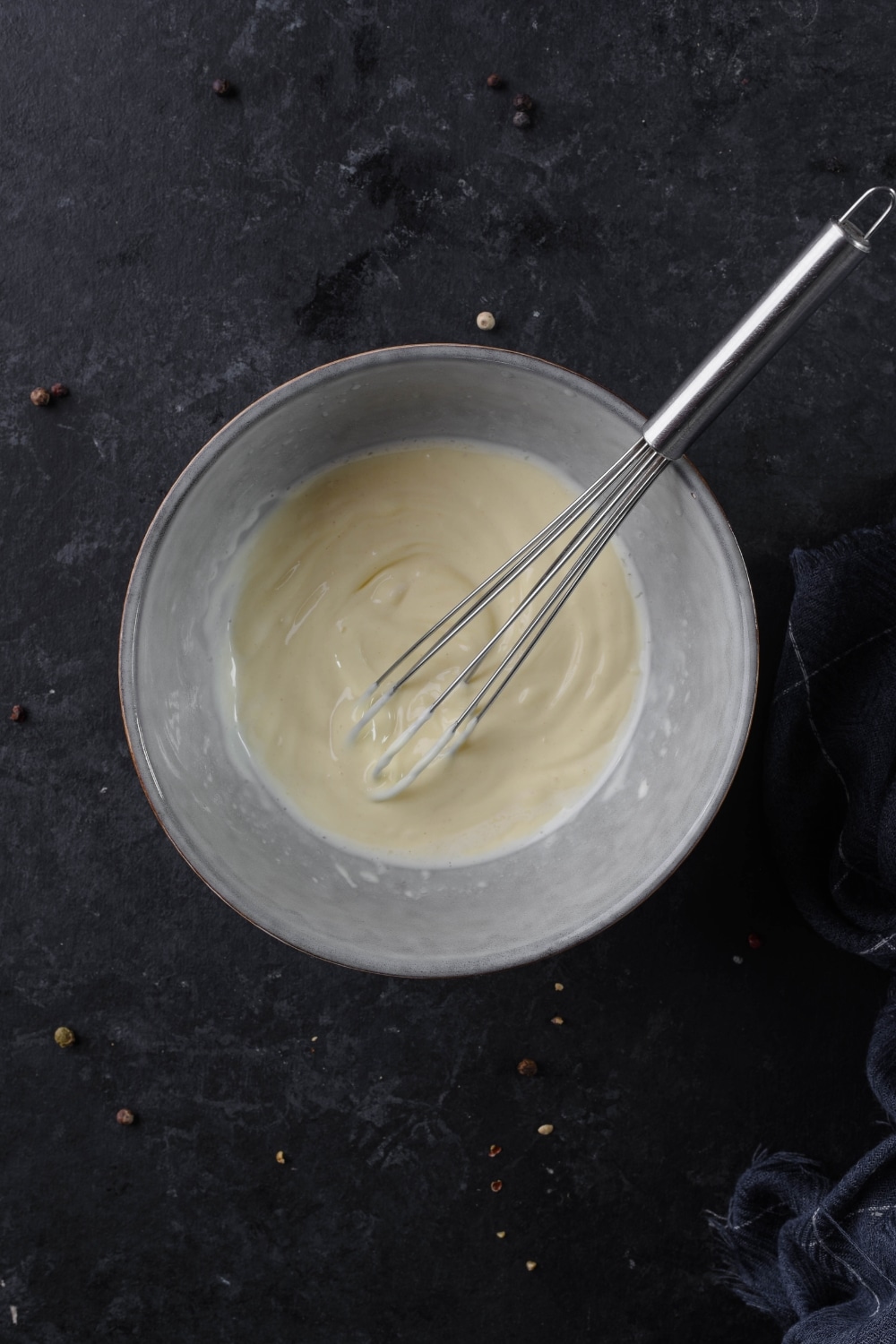 A bowl of lemon garlic aioli with a wire whisk.