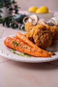 Grilled carrots topped with parsley and served with fried chicken.